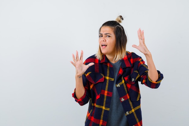 Cute lady raising hands, making wave in checked shirt and looking energetic