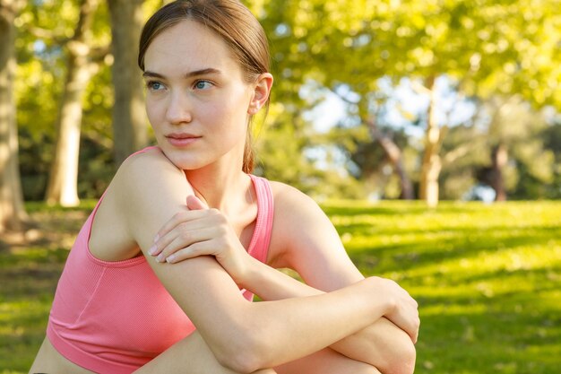 Cute lady sitting on the ground and looking aside at the park