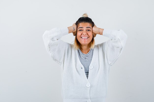 Tシャツのかわいい女性、手で頭を握りしめ、幸せそうに見えるカーディガン