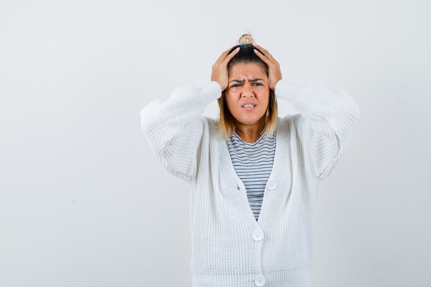 Cute lady in t-shirt, cardigan holding hands on head and looking distressed