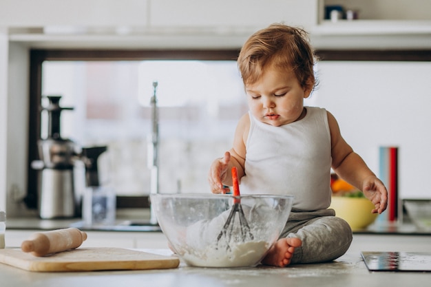 Cute little baby boy cooking at the kitchen