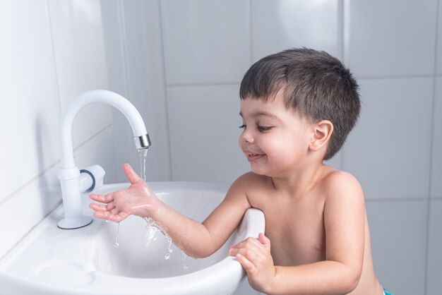 Cute little baby boy washing hand in bathroom sink