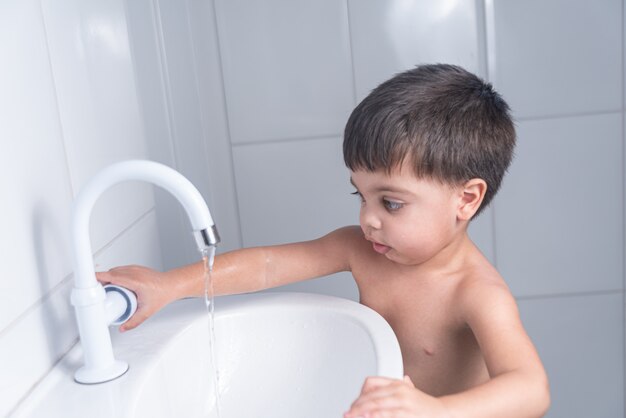 Cute little baby boy washing hand in bathroom sink