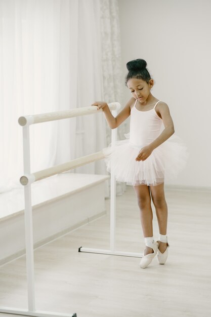 Cute little ballerina in pink ballet costume. Child in a pointe shoes is dancing in the room. Kid in dance class.