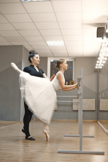 Милая маленькая балерина в белом балетном костюме. В комнате танцует барышня. Девушка в танцевальном классе с учителем.