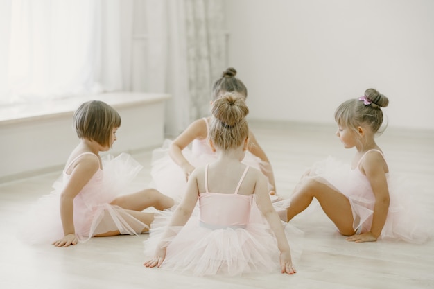 무료 사진 핑크 발레 의상을 입은 귀여운 작은 발레리나. 뾰족 구두를 신은 아이들이 방에서 춤을 추고 있습니다. 댄스 클래스에서 아이.