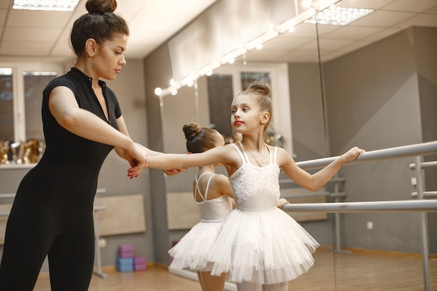 Cute little ballerinas in pink ballet costume. Children in a pointe shoes is dancing in the room. Kid in dance class with teacher.