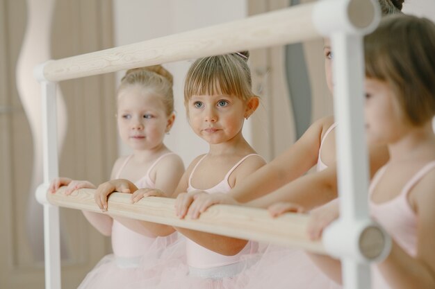 Cute little ballerinas in pink ballet costume. Children in a pointe shoes is dancing in the room. Kid in dance class.