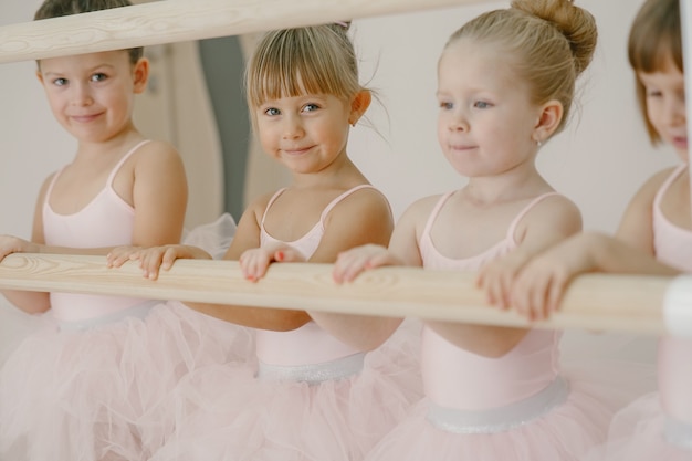Cute little ballerinas in pink ballet costume. Children in a pointe shoes is dancing in the room. Kid in dance class.