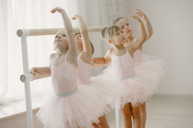 Cute little ballerinas in pink ballet costume. Children in a pointe shoes is dancing in the room. Kid in dance class.