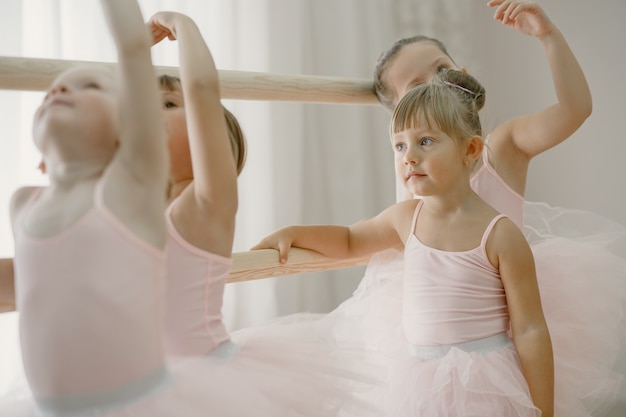 Cute little ballerinas in pink ballet costume. Children in a pointe shoes is dancing in the room. Kid in dance class.