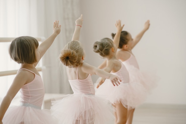 핑크 발레 의상을 입은 귀여운 작은 발레리나. 뾰족 구두를 신은 아이들이 방에서 춤을 추고 있습니다.