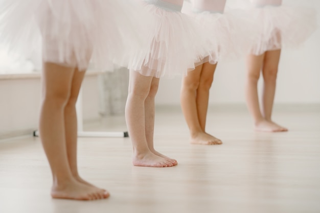 ピンクのバレエ衣装のかわいい小さなバレリーナ。トウシューズを履いた子供たちが部屋で踊っています