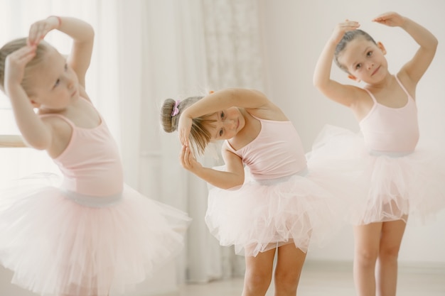 Free photo cute little ballerinas in pink ballet costume. children in a pointe shoes is dancing in the room