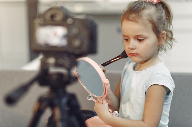 Free photo cute little blogger with cosmetics recording video at home