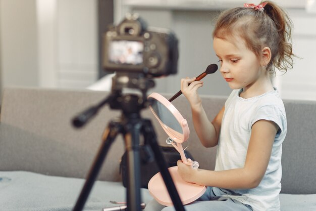 Cute little blogger with cosmetics recording video at home