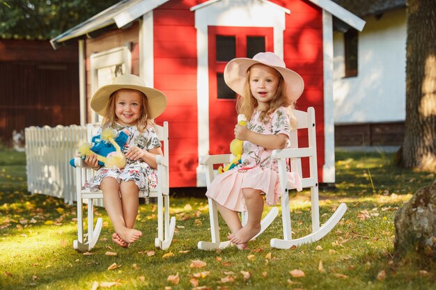 夏の柔らかいおもちゃでフィールドに座っている帽子のかわいい金髪の女の子。
