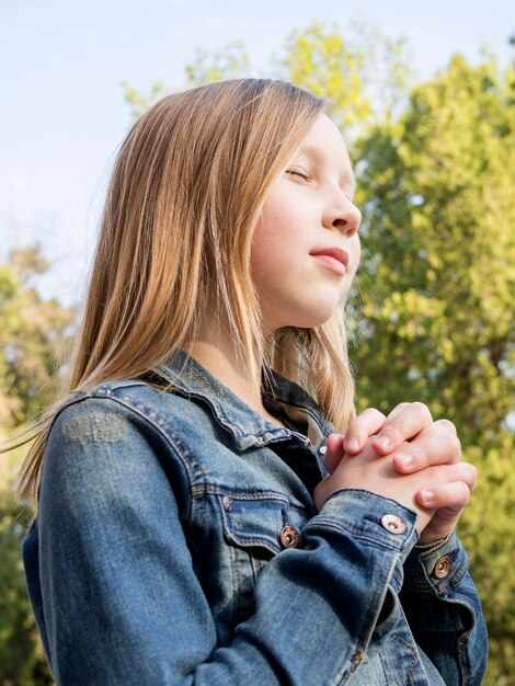 Cute little blonde girl praying