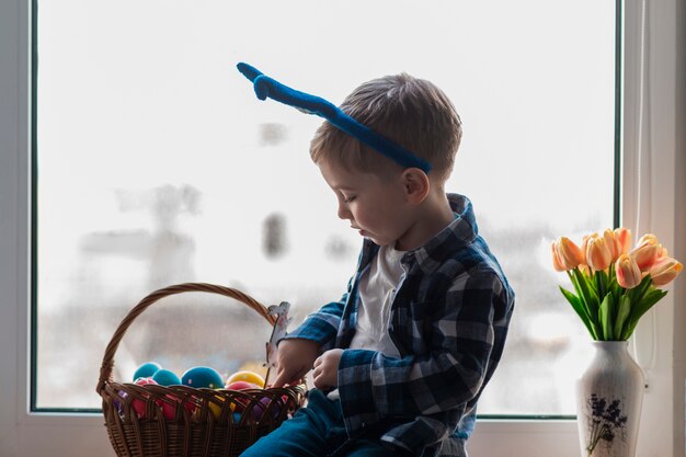 Cute little boy checking basket with eggs