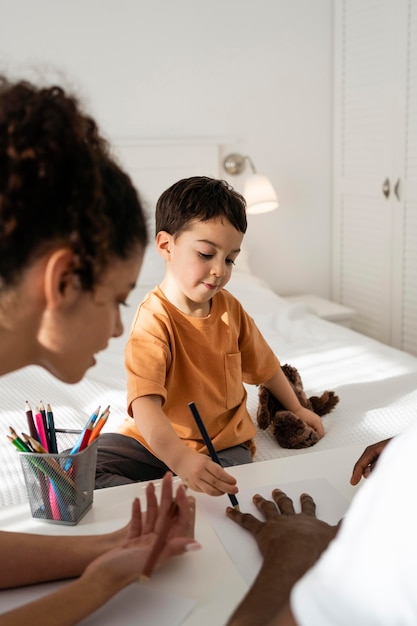 Cute little boy drawing his father hand on paper