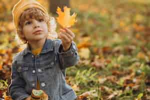 Free photo cute little boy eating croissant in park