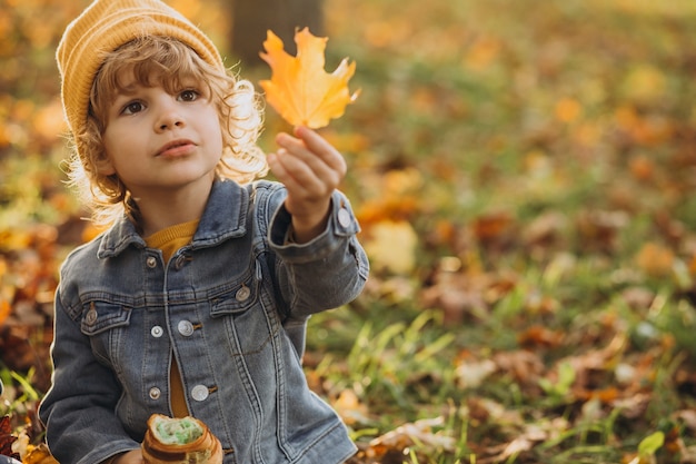 Cute little boy eating croissant in park