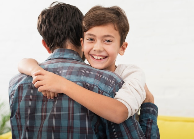 Foto gratuita ragazzino sveglio che abbraccia suo padre