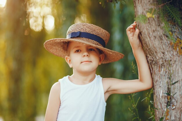 帽子のかわいい男の子は夏の公園で時間を過ごす