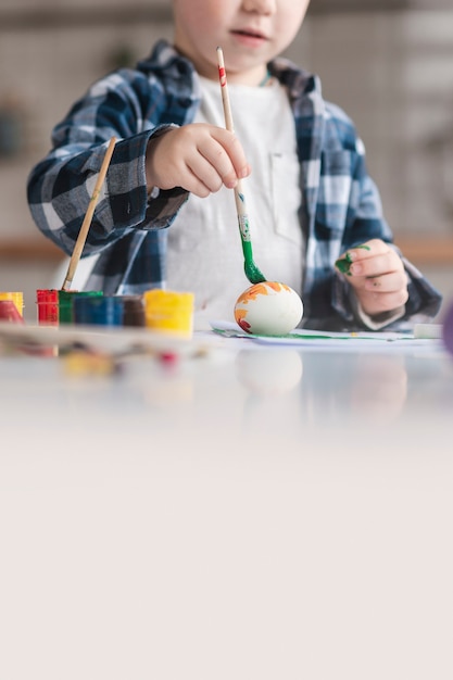 Free photo cute little boy painting eggs for easter