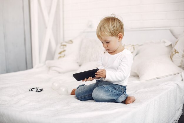 Cute little boy playing with a laptop on a bed