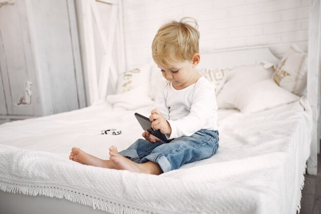 Милый маленький мальчик, играя с ноутбуком на кровати