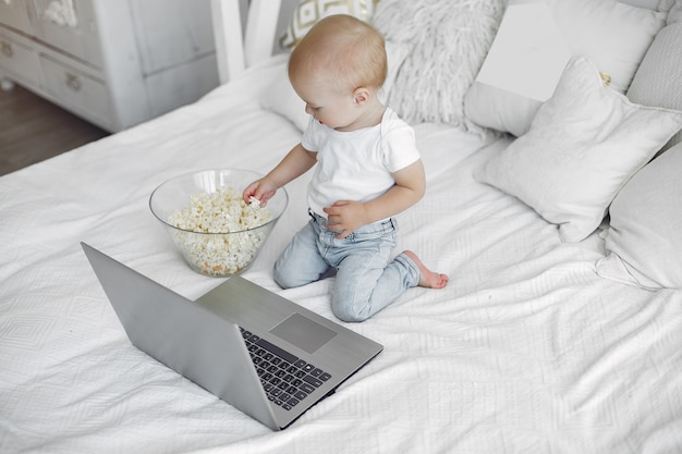 Cute little boy playing with a laptop on a bed