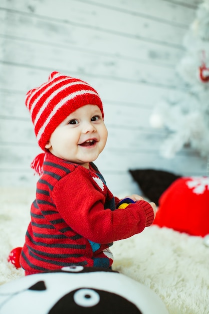 Cute little boy in a red striped hat sits on the floor