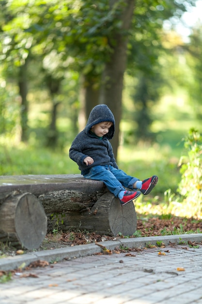 Cute little boy resting on a wooden bench