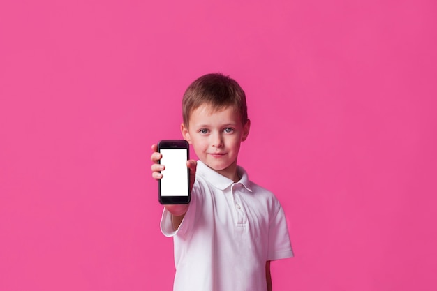 Cute little boy showing blank screen cellphone on pink background