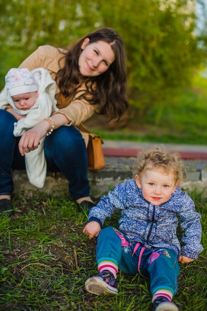 Cute little boy sitting on the grass with his mother background