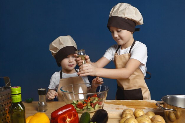 cute little boy wearing chef hat standing at kitchen table