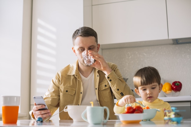 Cute little child and his father eating breakfast