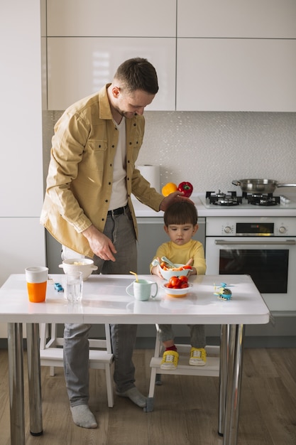 かわいい小さな子供と彼の父親が台所で時間を過ごす