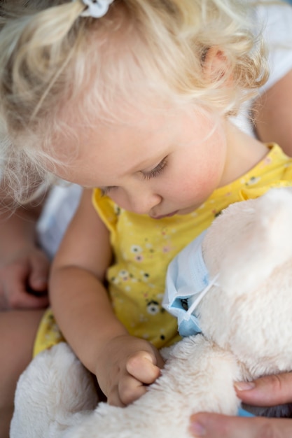 Cute little child playing with toy with medical mask