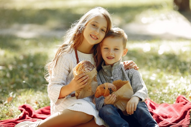 Cute little children sitting in a park with bread