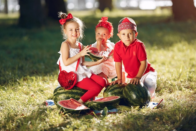 Piccoli bambini svegli con le angurie in un parco