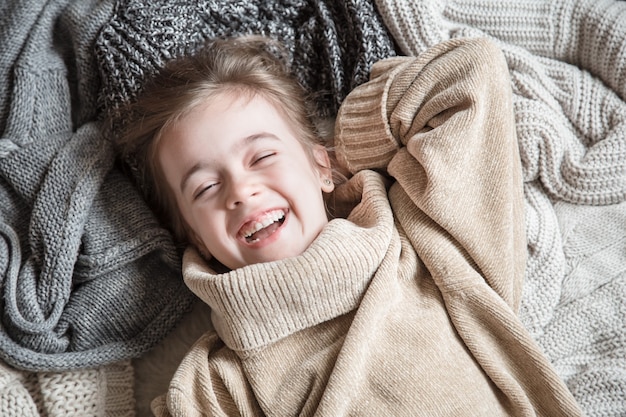 Cute little fun girl in a knitted sweater.