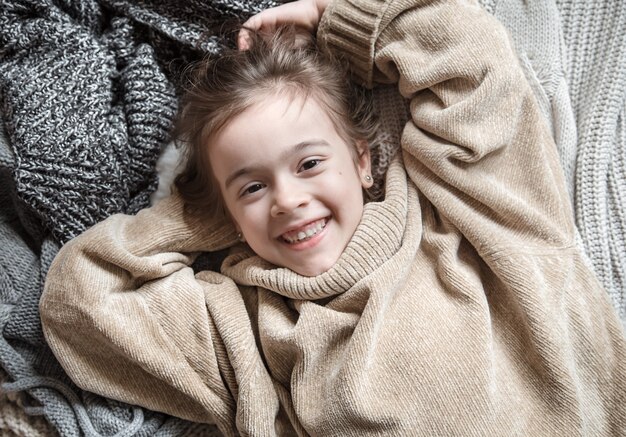 Cute little fun girl in a knitted sweater.