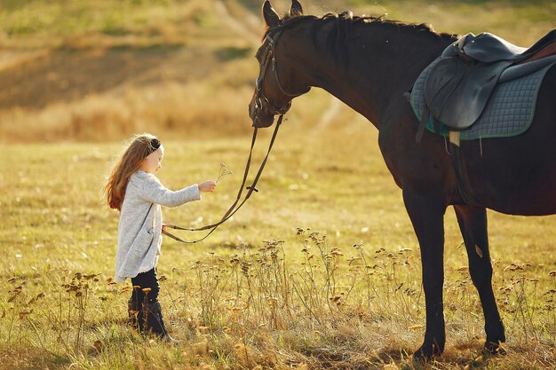 Cute little girl in a autumn field with horse