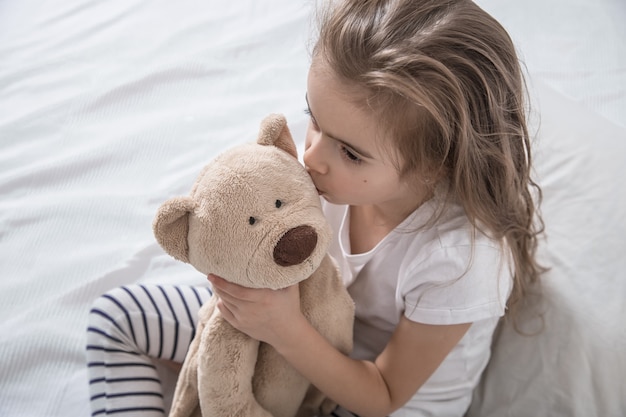 Cute little girl in bed with soft toy