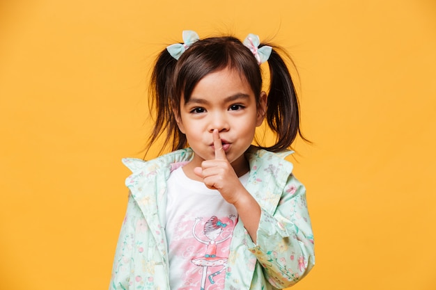 Cute little girl child showing silence gesture.