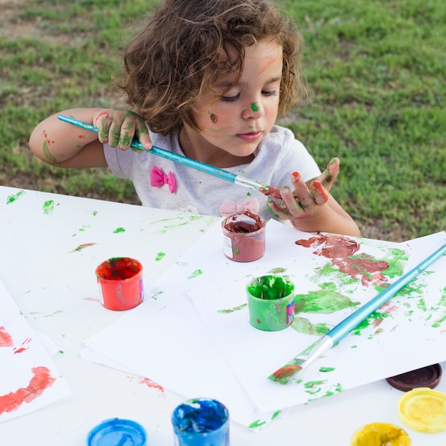 Cute little girl drawing painting on canvas in park
