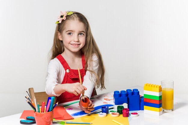 Cute little girl drawing with paint and paintbrush at home