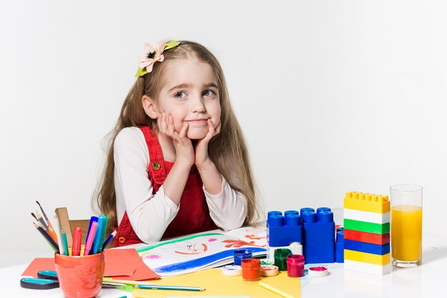 Cute little girl drawing with paint and paintbrush at home